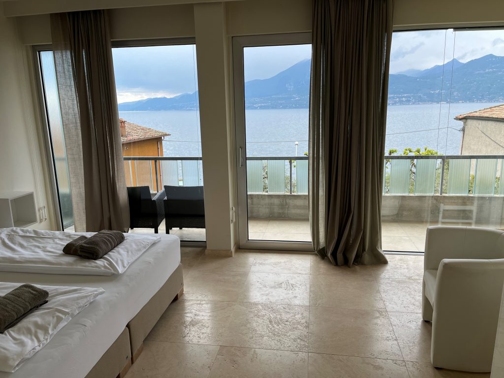 Wohnraum mit extra-light geschliffenen Travertin Natursteinfliesen und großer Fensterfront mit Seeblick