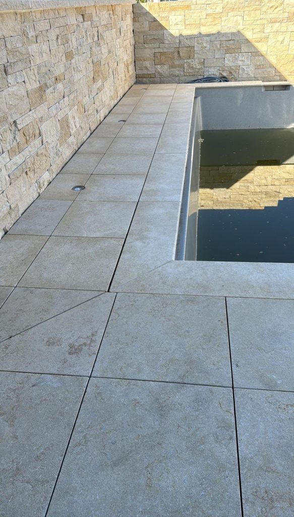Naturstein-Terrassenplatten Seashell Light aus Kalkstein am Pool verlegt, rutschhemmende Oberfläche in heller Farbgebung